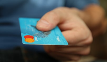 A close-up of a hand holding a blue bank card