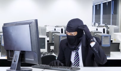 A man in costume sits behind a computer screen