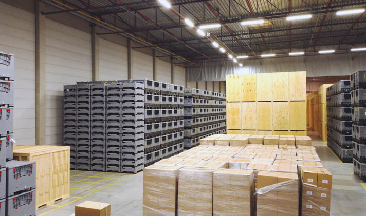 A storage space filled with numerous boxes, pallets, and wooden lift vans.