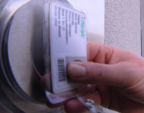A person scans a plastic access pass with a barcode.