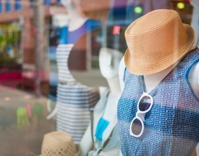 Een close-up van een vitrine van een kledingwinkel met die zomers geklede paspoppen